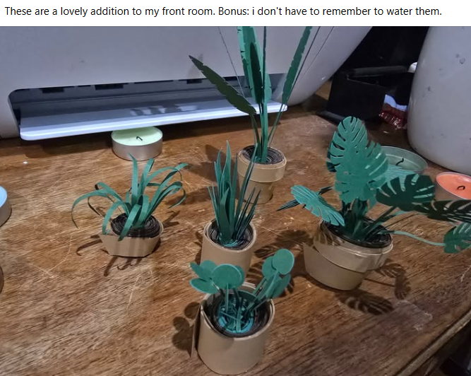 Community share: a little forest of paper houseplants on a wooden table.